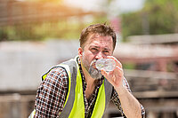 Arbeiter trinkt Wasser auf einer Baustelle. Bauingenieur trinkt Wasser bei der Arbeit auf der Baustelle.